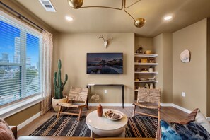 Una sala de estar moderna con un ventanal grande, un cactus, una chimenea y vistas a la ciudad.