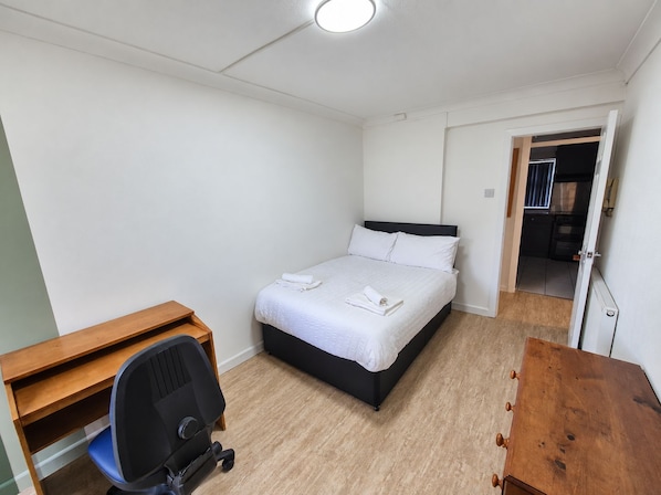 Ein Schlafzimmer mit einem Bett, einem Schreibtisch und einem Stuhl.