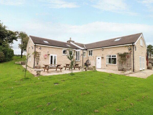A two-story stone house with a patio area, outdoor seating, and a small garden. - Greystones - C (Buxton)