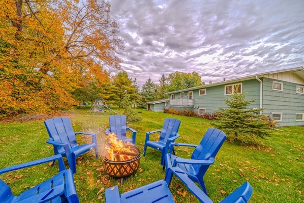 A backyard with a fire pit and four blue chairs arranged around it. - Sauna | Cozy Lake Retreat | Dock Kayaks Canoe (Bemidji)