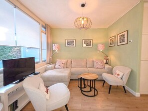 Ein Wohnzimmer mit einer Couch, zwei Sesseln, einem Fernseher und einem kleinen Tisch.