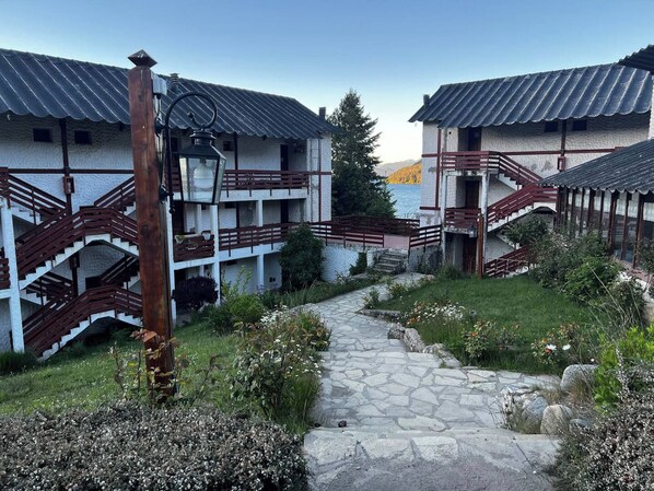 Un cortile con sentieri in pietra, ringhiere in legno ed edifici dalle tetti in metallo.