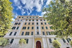 A multi-story building with a symmetrical facade, large windows, and a central entrance with a decorative arch. - 4BNB - Eroi Vatican Apartment (Rome)