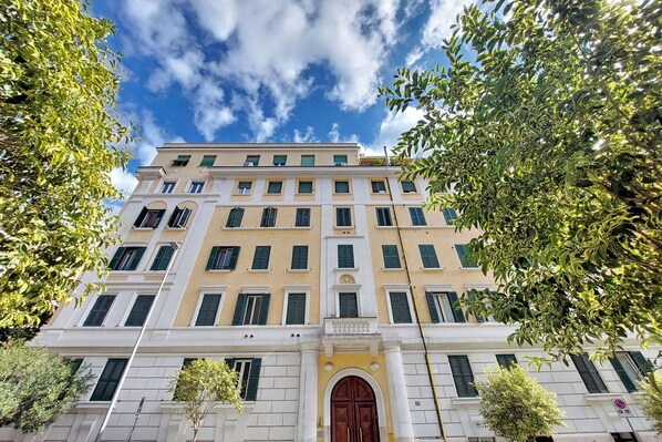 A multi-story building with a symmetrical facade, large windows, and a central entrance with a decorative arch. - 4BNB - Eroi Vatican Apartment (Rome)