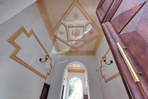 Een interieur met een gewelfde plafond, geometrische muurpatronen en een houten deur.