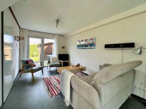 A modern living room with a sofa, a coffee table, a TV, and a painting on the wall. - Holiday Home With 2 Bedrooms (Oostkapelle)