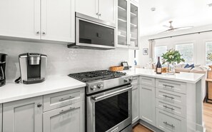 Cozinha moderna com micro-ondas embutido, máquina de café, fogão a gás e forno.