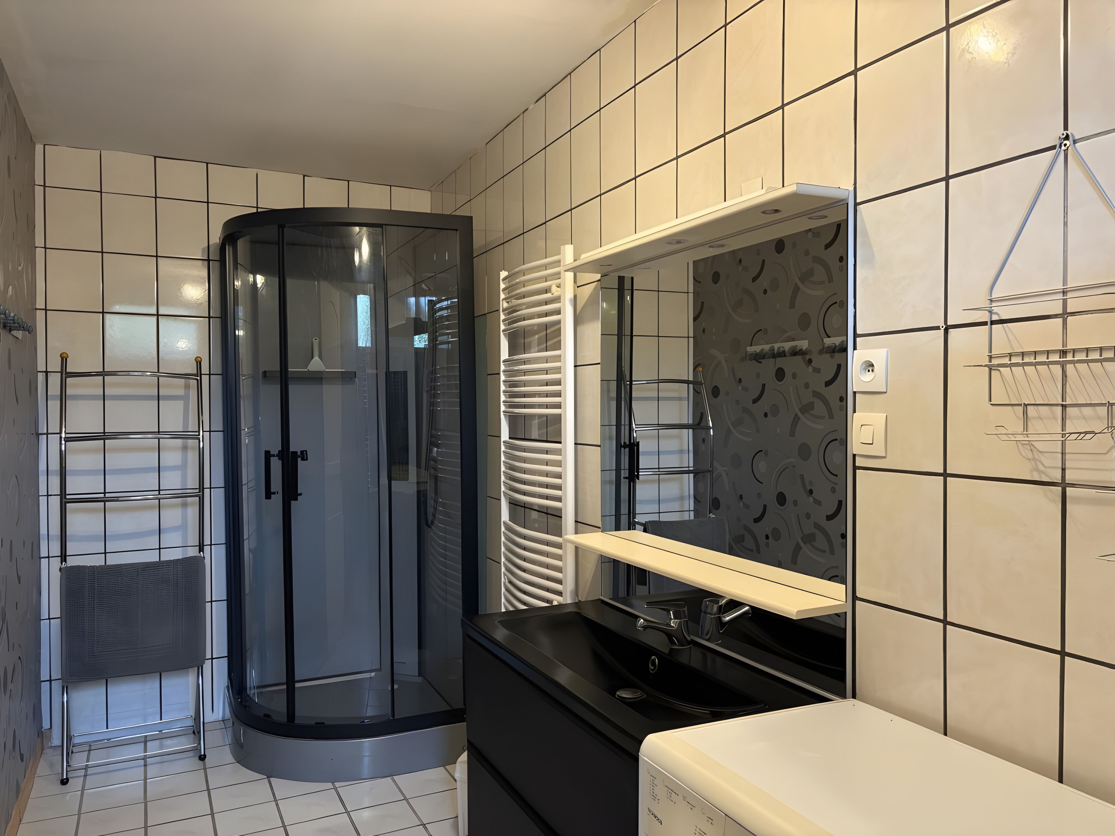 A modern bathroom with a glass shower enclosure, a vanity with a mirror, and a towel rack.