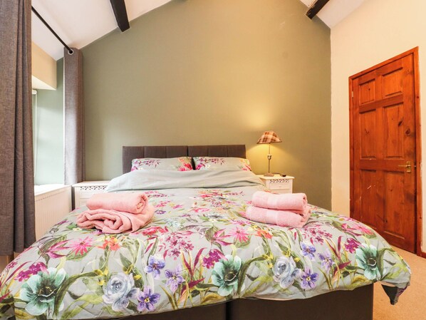 A bedroom with a bed, a nightstand, a lamp, and a wooden door. - Ty Driffter (Porthmadog)