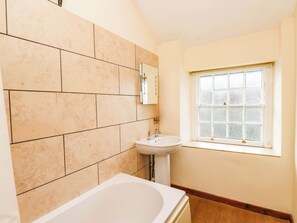 A bathroom with a bathtub, a sink, and a window. - Ty Driffter (Porthmadog)