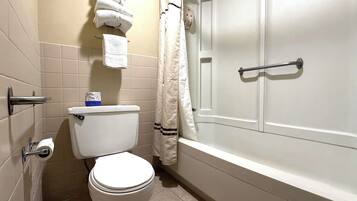 A bathroom with a toilet, a towel rack, a shower curtain, and a bathtub.