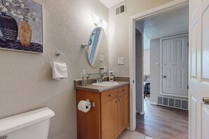 Un baño con inodoro, lavamanos, tocador y espejo con luz.