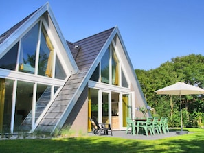 A modern house with a sloped roof, large windows, and a patio with outdoor furniture. - Villa in Callantsoog With Swimming Pool (Callantsoog)