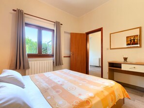 A bedroom with a bed, a window with curtains, a wooden door, a dresser, and a mirror. - Casa Parenzana With Pool (Vizinada)