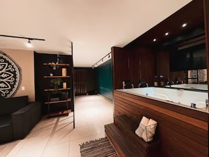 A modern bathroom with a large bathtub, wooden paneling, and a mirror. - Oasis Loft Friends (Medellín)