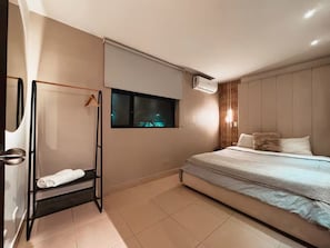 A bedroom with a bed, a window, a wall-mounted air conditioner, and a towel rack. - Oasis Loft Friends (Medellín)