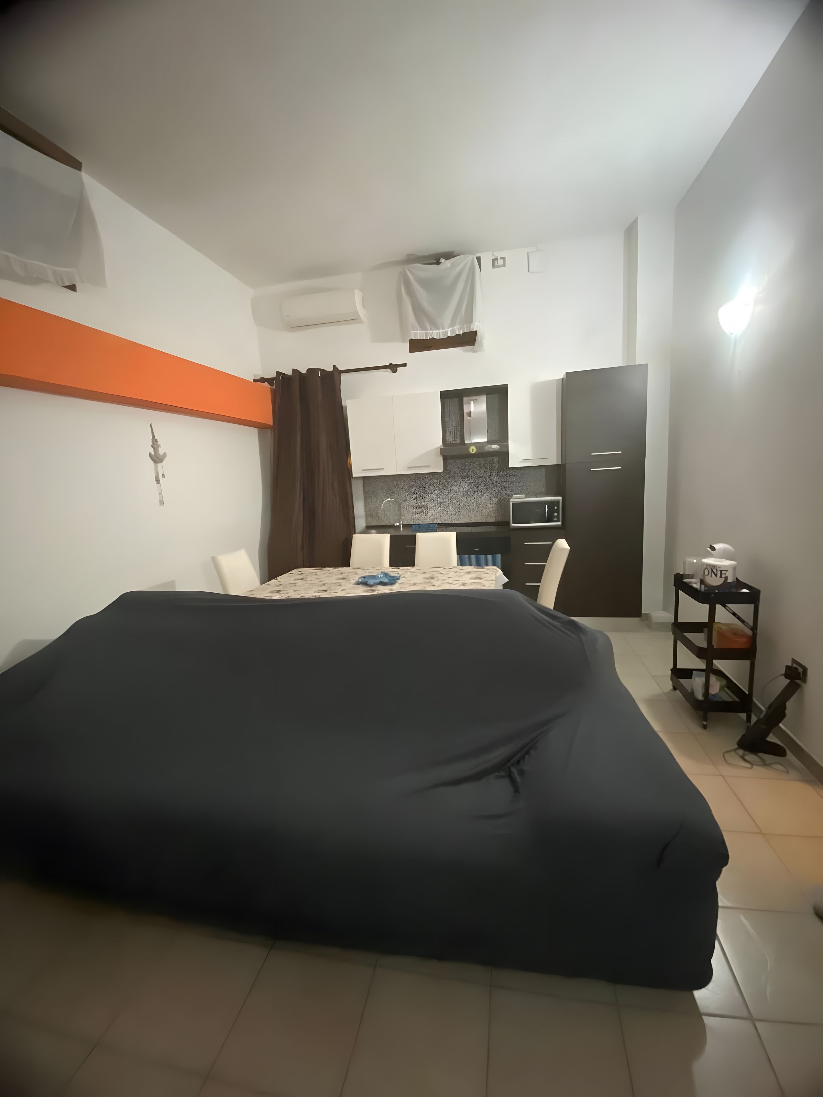 A hotel room with a bed, a small kitchenette, a dining table, and a single chair.