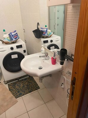 Ein Badezimmer mit Waschbecken, Waschmaschine und Dusche.