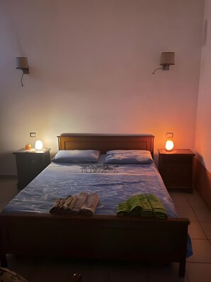 Ein Schlafzimmer mit einem Bett, zwei Nachttischen mit Lampen, einem Beistelltisch und einer Wandleuchte.