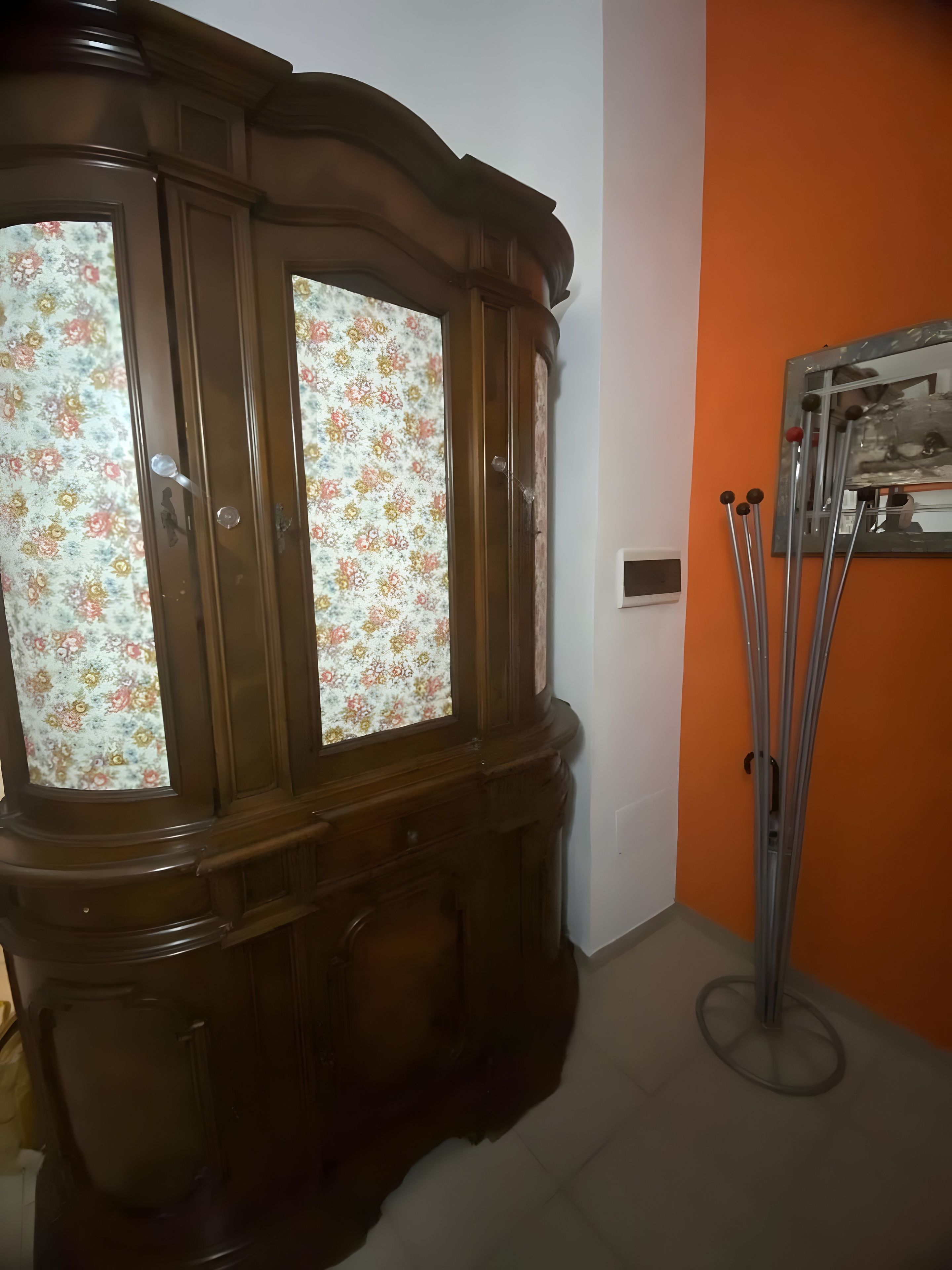 Un armario de madera con puertas de cristal, un espejo y un soporte metálico con barras.