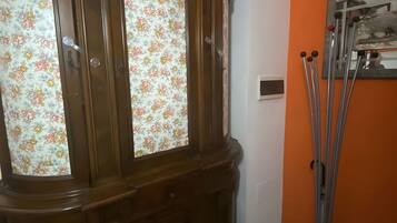 Un armario de madera con puertas de cristal, un espejo y un soporte metálico con barras.