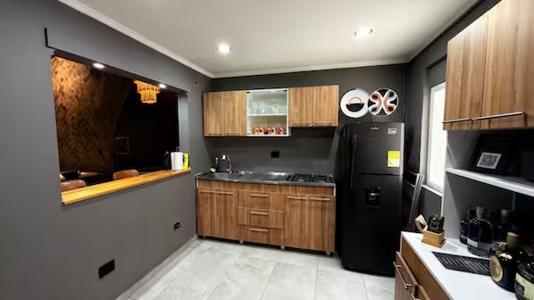 A modern kitchen with wooden cabinets, a black refrigerator, and a built-in oven. - BEST Apartment in Manila with a Jacuzzi (Medellín)