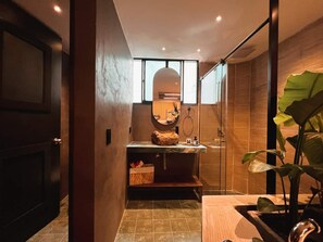 Un baño moderno con cabina de ducha de vidrio, tocador de madera y un espejo grande.