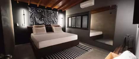 A modern bedroom with a large bed, a wall-mounted vanity, and a unique tapestry.