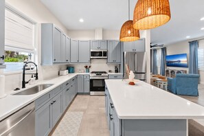 A modern kitchen with grey cabinets, stainless steel appliances, and a large island. - NEW I Pool & Spa Retreat, Golf Course, Game Room, 5 Min Downtown, 10 Min Beach (Melbourne)