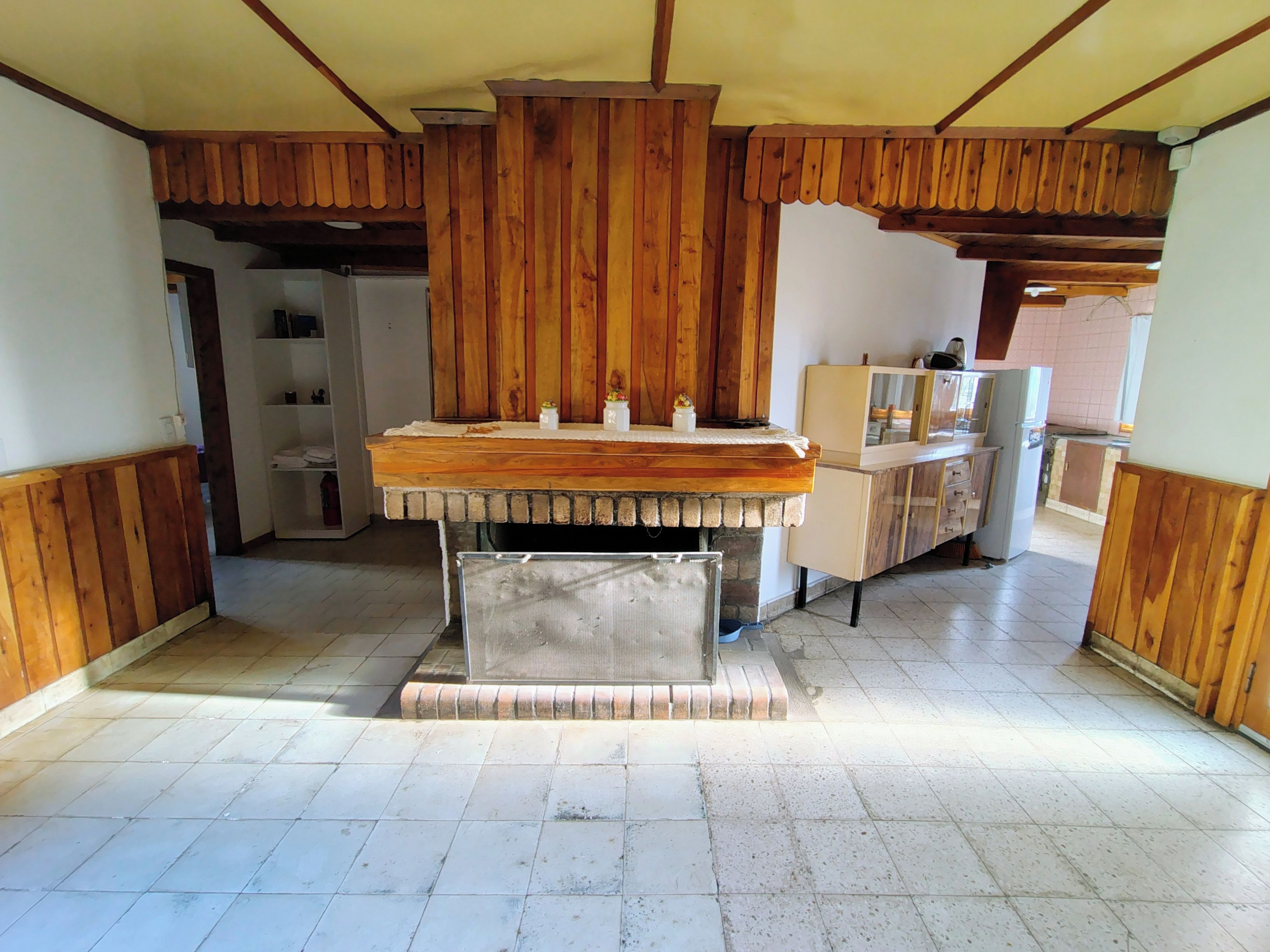 A kitchen with wooden paneling, a central island, and a tiled floor.