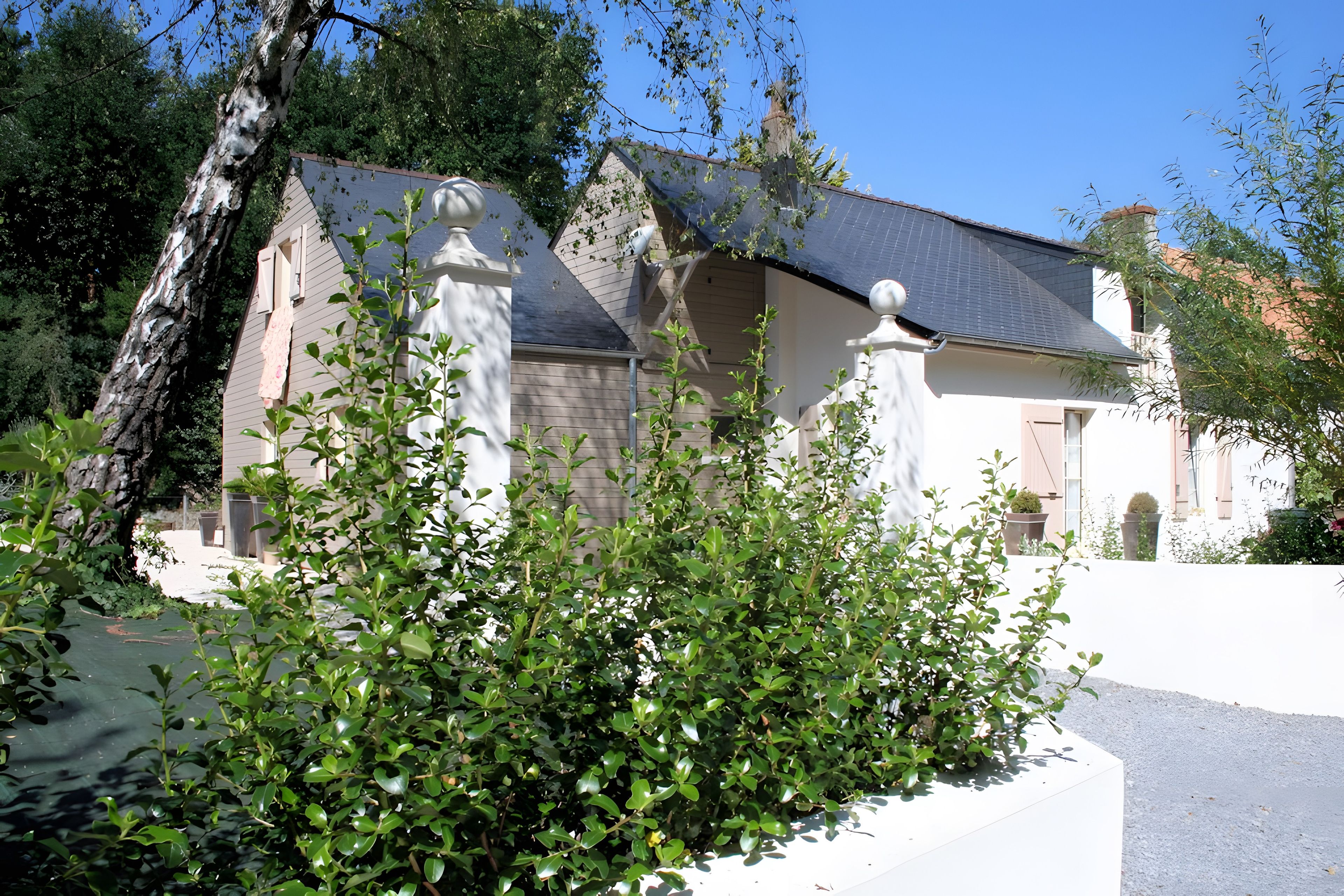 A building with a sloped roof, surrounded by greenery and trees.