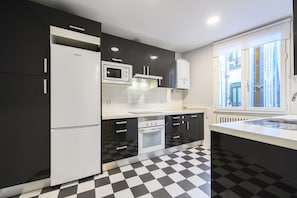A modern kitchen with black and white checkered flooring, a built-in microwave, and a refrigerator. - M Fer54d Luminoso Piso de 2 Dormitorios con Balco (Madrid)