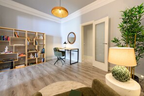 A modern living room with a wooden bookshelf, a desk, a chair, a round mirror, a lamp, and a potted plant. - M Fer54d Luminoso Piso de 2 Dormitorios con Balco (Madrid)
