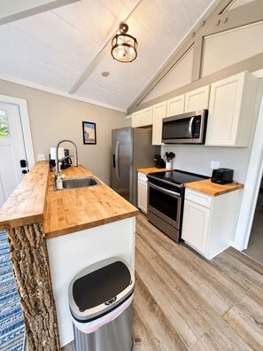 A modern kitchen with a wooden countertop, stainless steel appliances, and a trash can. - Slopesider 11 Ski-In Ski-Out Home with view and deck (Sugar Mountain)