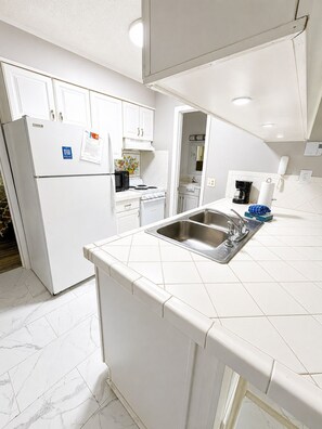 A modern kitchen with white cabinetry, a stainless steel sink, and a microwave. - Powder Pad | Walk to Slopes • Fireplace • Deck (Beech Mountain)