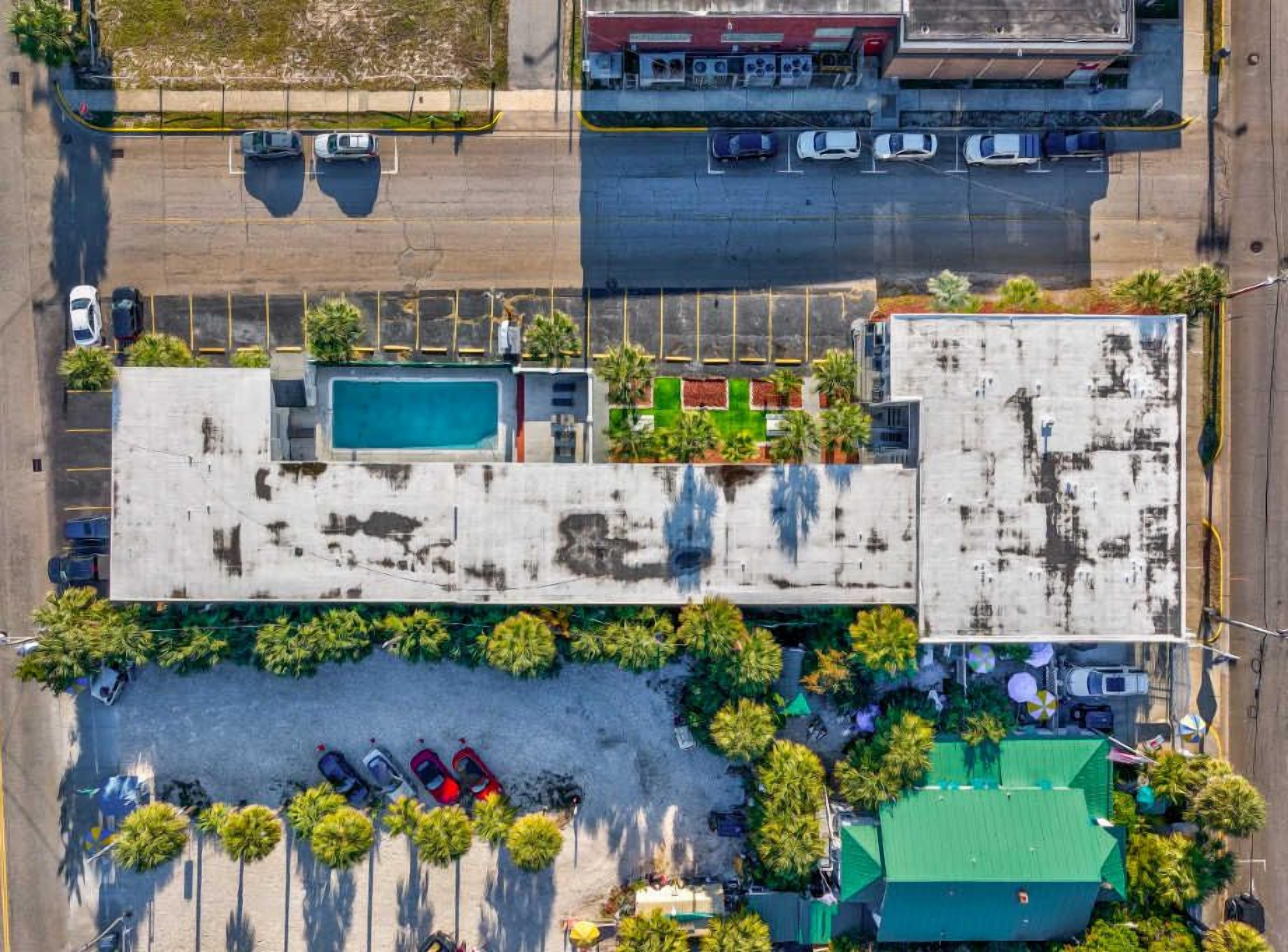 Luchtbeeld van een gebouw met een zwembad, parkeerplaats en constructies met groene daken.