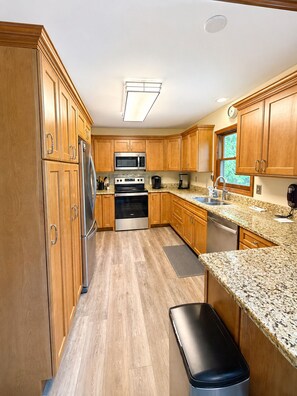 A kitchen with wooden cabinets, stainless steel appliances, granite countertops, and a window with a view. - Creekside Perch - Relax - Unwind - Creekside (Beech Mountain)