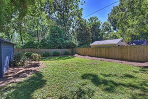 A backyard with a wooden fence, a shed, and a lawn. - Charming Historic Bungalow · Walkable to Eats/Park (Charlotte)