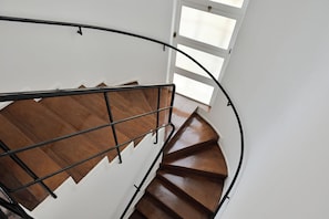 Una escalera en espiral con escalones de madera y barandilla metálica.