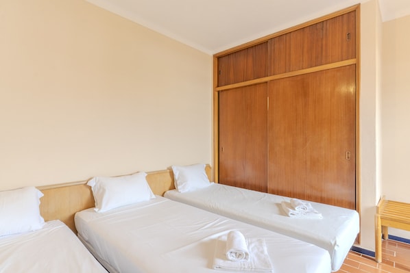 Ein Hotelzimmer mit zwei Betten, einem Holzschrank und einem kleinen Holztisch.