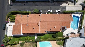 Vista aérea de uma propriedade com piscina, varanda coberta e área de estacionamento.