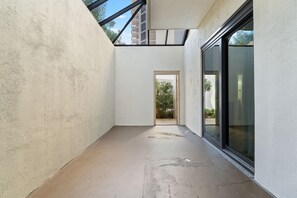 A narrow corridor with a skylight, a glass door leading outside, and a concrete floor. - Phoenix East 011 (Orange Beach)