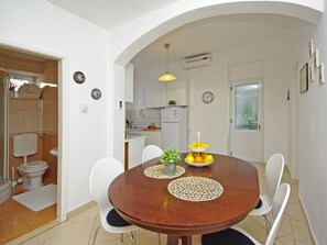 A dining area with a round wooden table, white chairs, and a central decorative item. - Beach House Ivana App.2 (Gradac)