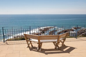 A wooden bench overlooking a rocky coastline with the ocean in the background. - Devon Beach Court (Woolacombe)