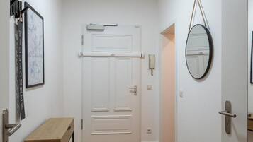 Ein Flur mit Holzboden, einer weißen Tür, einem kleinen Tisch und einem gerahmten Bild an der Wand.