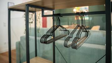 Ein Zimmer mit einer Glastrennwand, einem Holztisch und einem Metallkleiderständer.