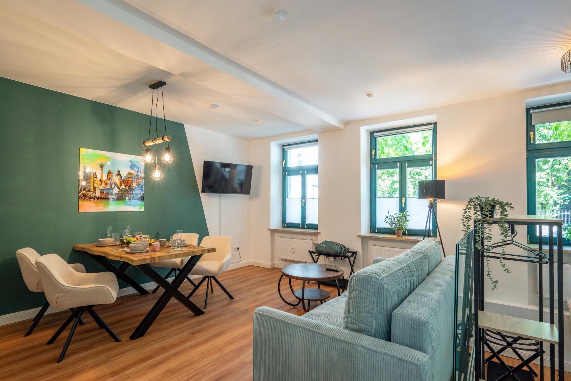 A modern living room with a dining area, a sofa, a TV, and a painting on the wall.