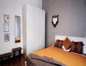A bedroom with a bed, a wardrobe, a mirror, and a wall-mounted coat rack. - Charming Apartment in Duomo (Milan)