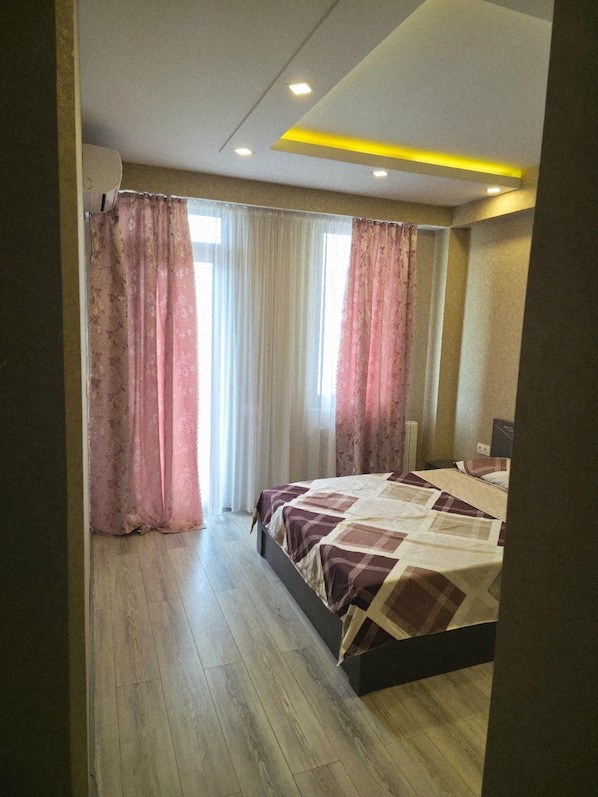 Ein Schlafzimmer mit Bett, Vorhängen und einer Deckenleuchte.
