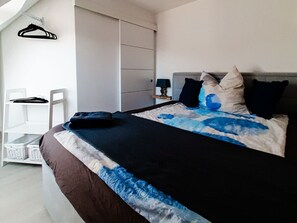 A bedroom with a bed, a wardrobe, a chair, and a small table with a lamp. - Terraced House With 1 Bedroom (Maasholm)